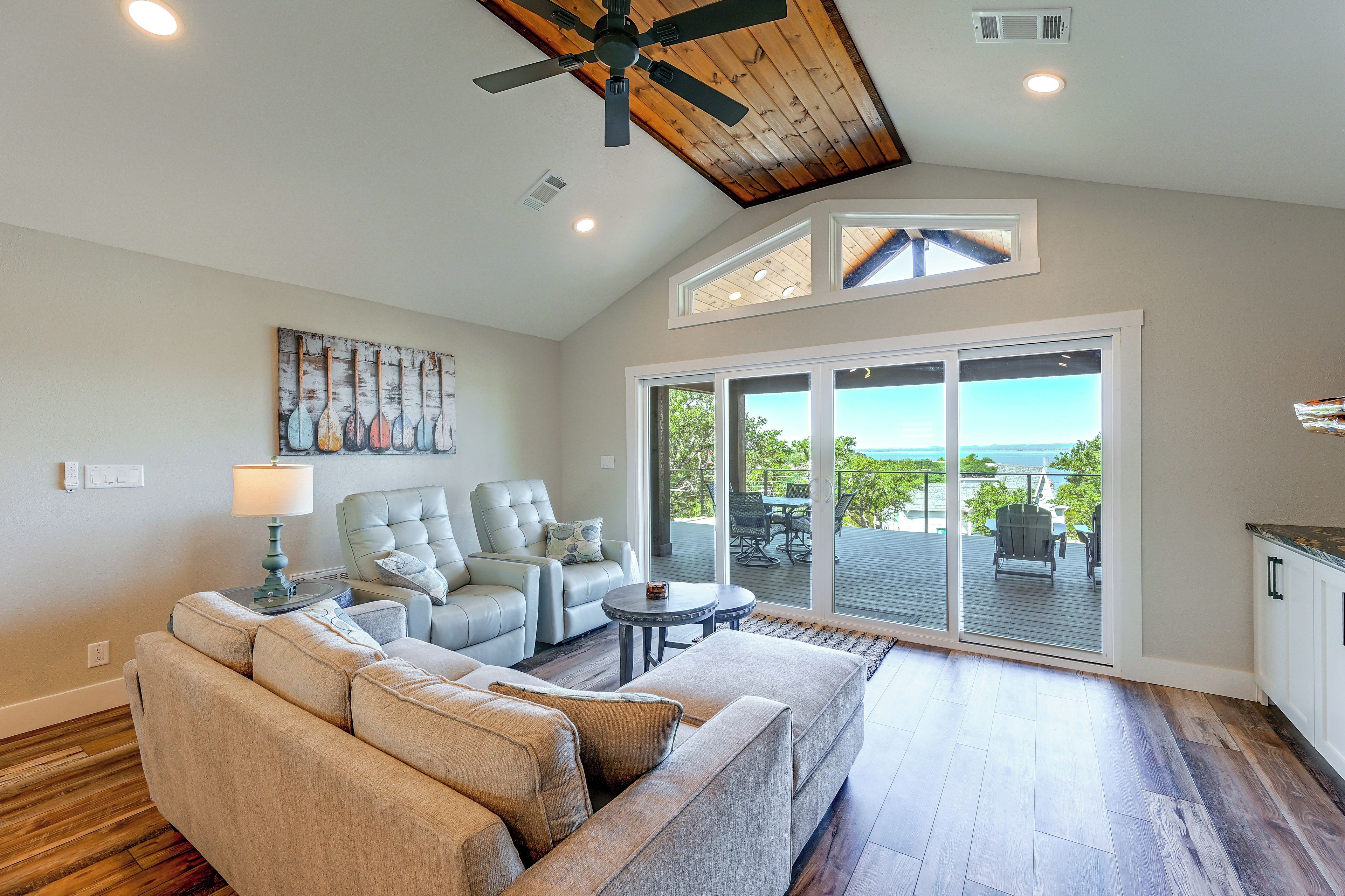 A spacious living room with a ceiling fan, a large window, and a view of the outdoors.