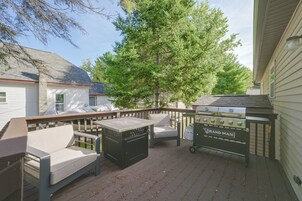Una terraza con mobiliario exterior, una parrilla y un árbol grande.