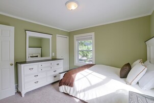 Un dormitorio con cama, cómoda y ventana.