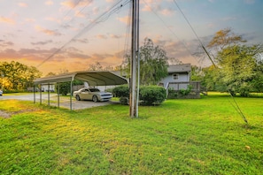 A residential area with a covered carport, a house, and a well-maintained lawn.