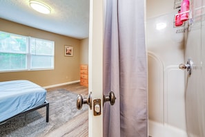 A bedroom with a bed, a dresser, and a shower.