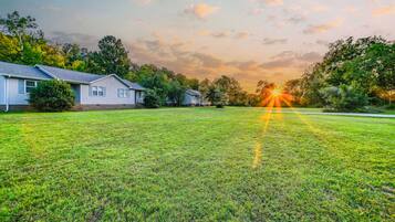 A residential area with houses, a grassy lawn, and trees.