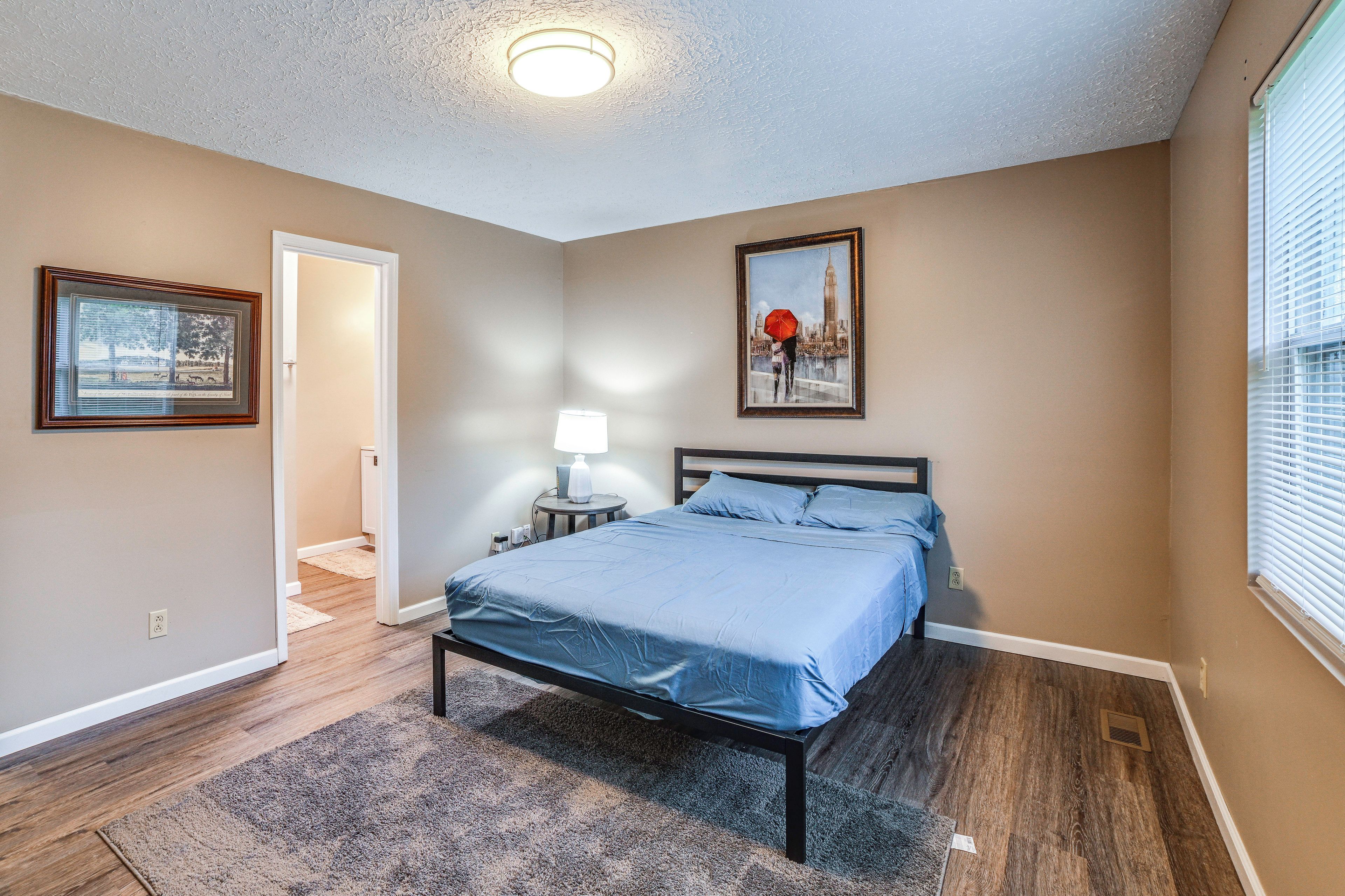 A bedroom with a bed, a nightstand, a lamp, and a framed picture on the wall.