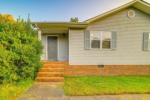 A single-story house with a front door, a small porch, and a brick foundation.
