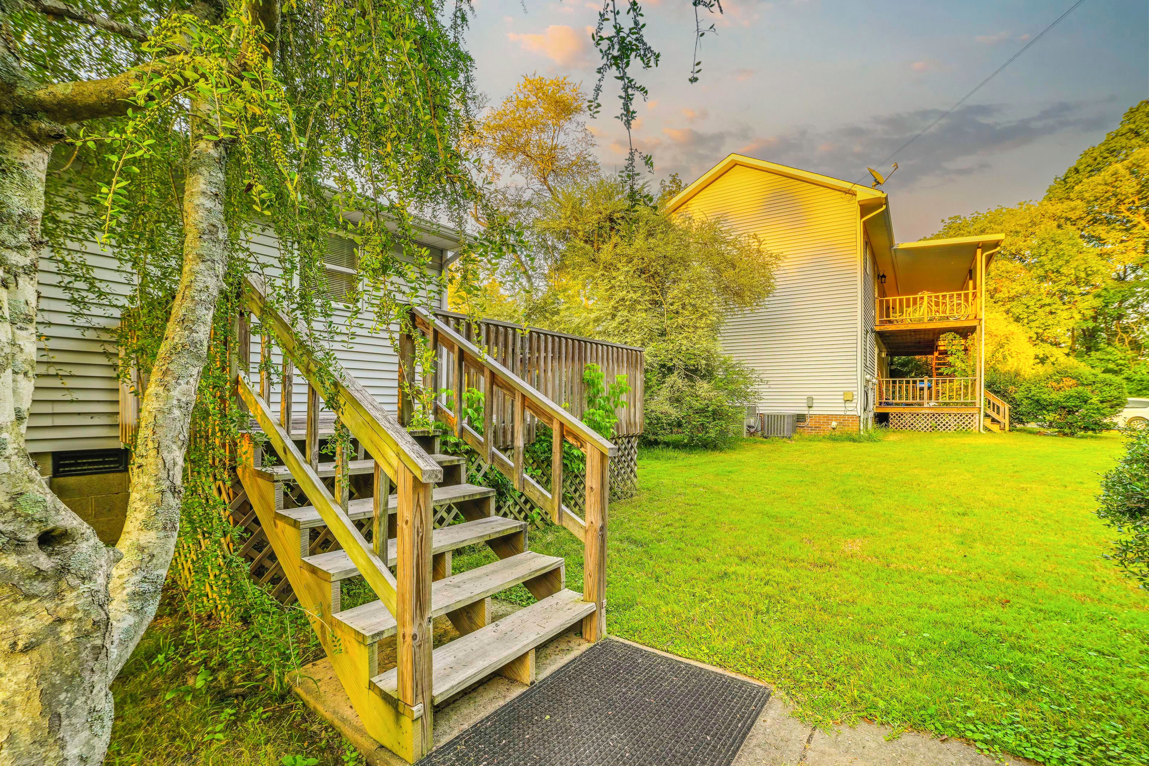A residential property with a wooden staircase leading to a front porch, a well-maintained lawn, and a house with a yellow exterior.