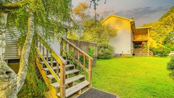 A residential property with a wooden staircase leading to a front porch, a well-maintained lawn, and a house with a yellow exterior.