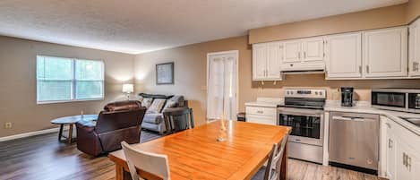 A modern kitchen with white cabinets, a built-in oven, microwave, and dishwasher.