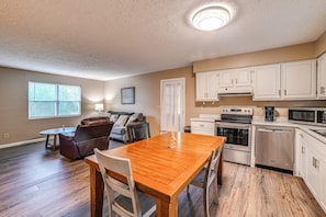 A modern kitchen with white cabinets, a built-in oven, microwave, and dishwasher.