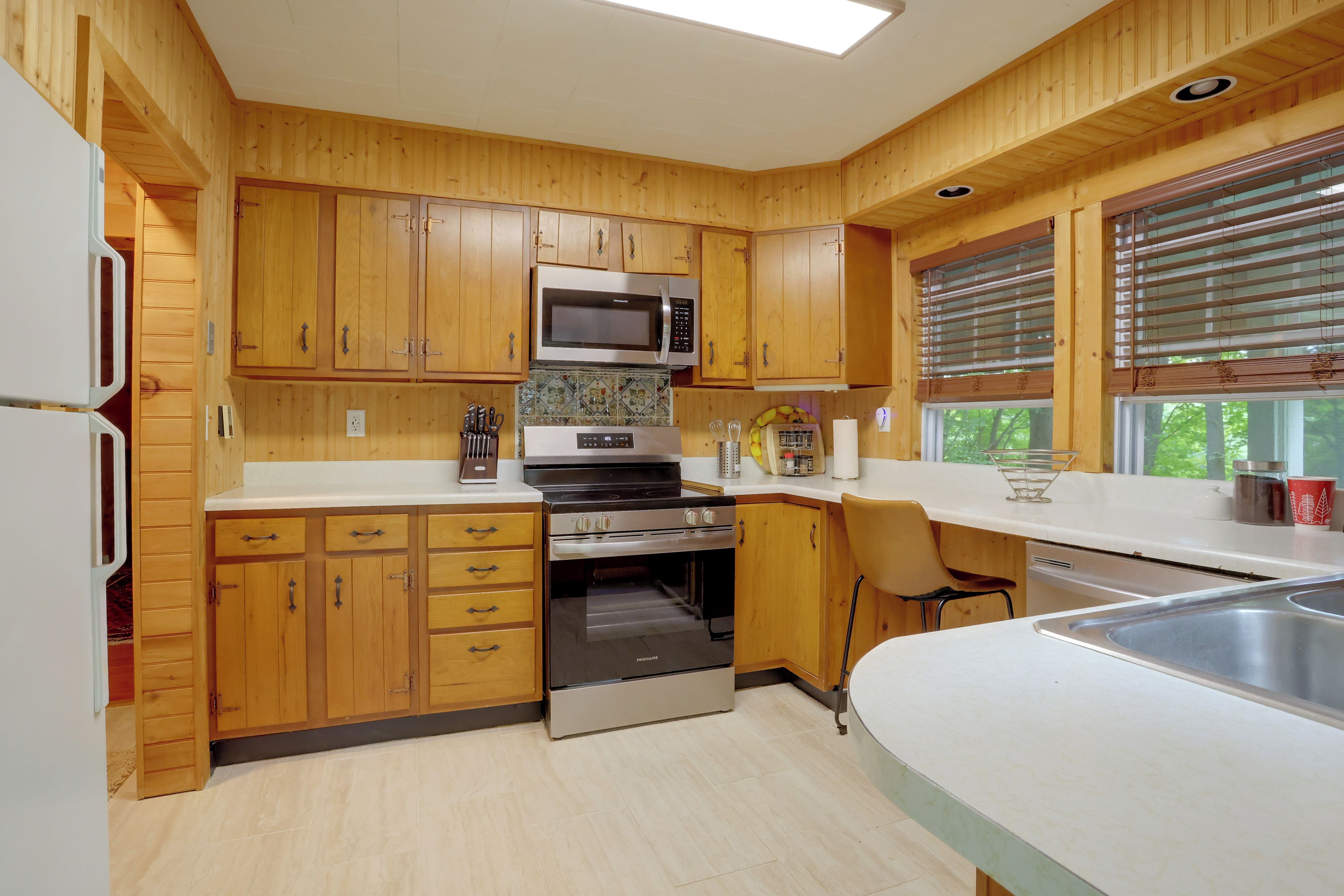 Una cocina con armarios de madera, microondas, estufa y lavaplatos.