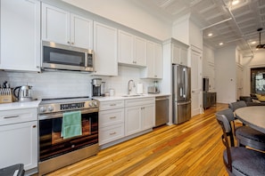 A modern kitchen with white cabinetry, stainless steel appliances, and a wooden floor. - Main St Magic: Walkable Salisbury Condo! (Salisbury)