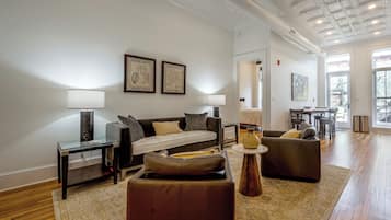 A modern living room with a sofa, armchairs, a coffee table, and a dining area with a table and chairs.