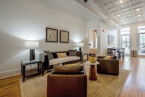 A modern living room with a sofa, armchairs, a coffee table, and a dining area with a table and chairs. - Main St Magic: Walkable Salisbury Condo! (Salisbury)