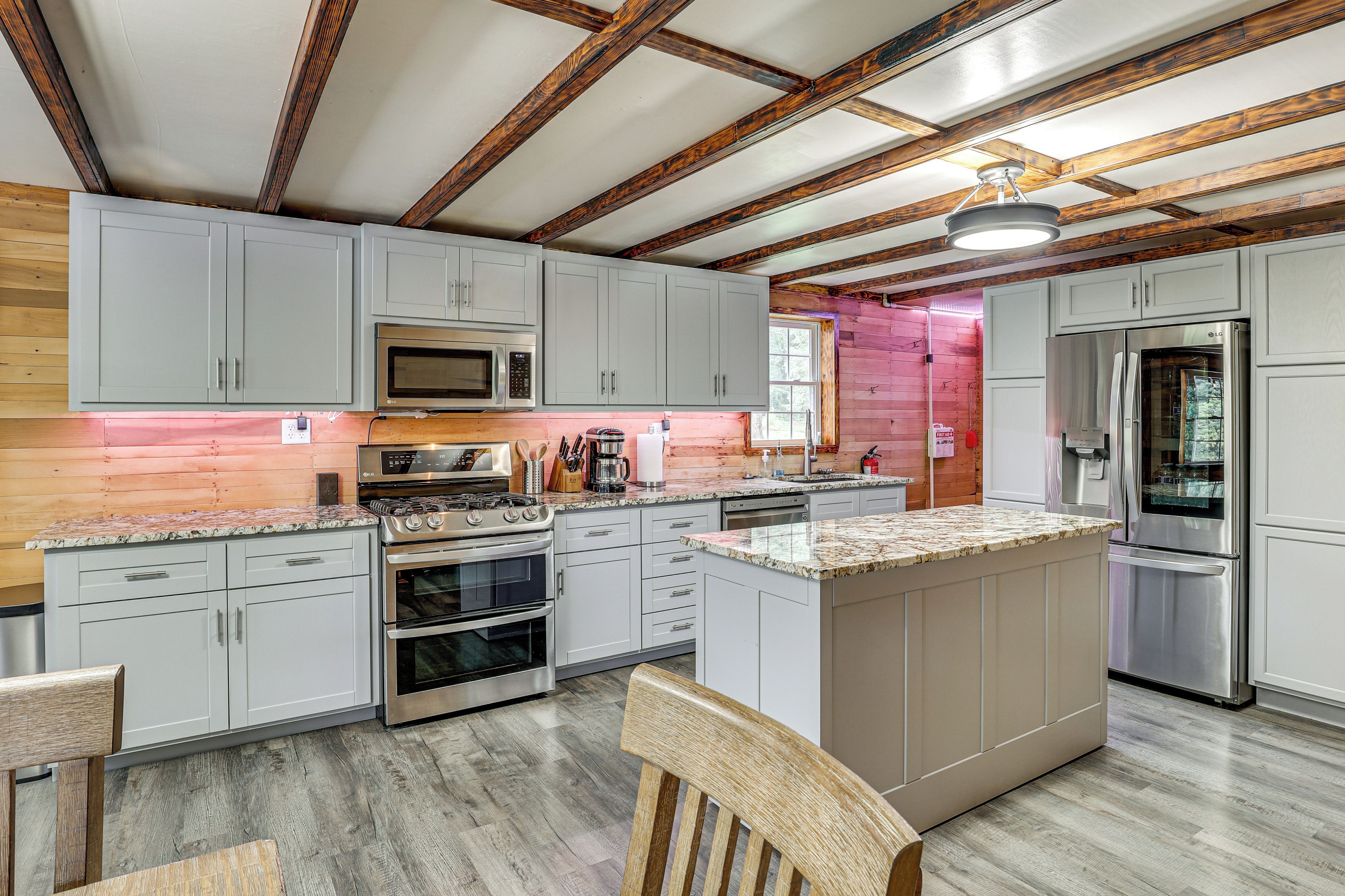 A kitchen with white cabinets, stainless steel appliances, and a wooden ceiling.