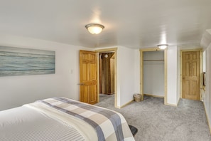A bedroom with a bed, a wooden door, a closet, and a hallway leading to another room.
