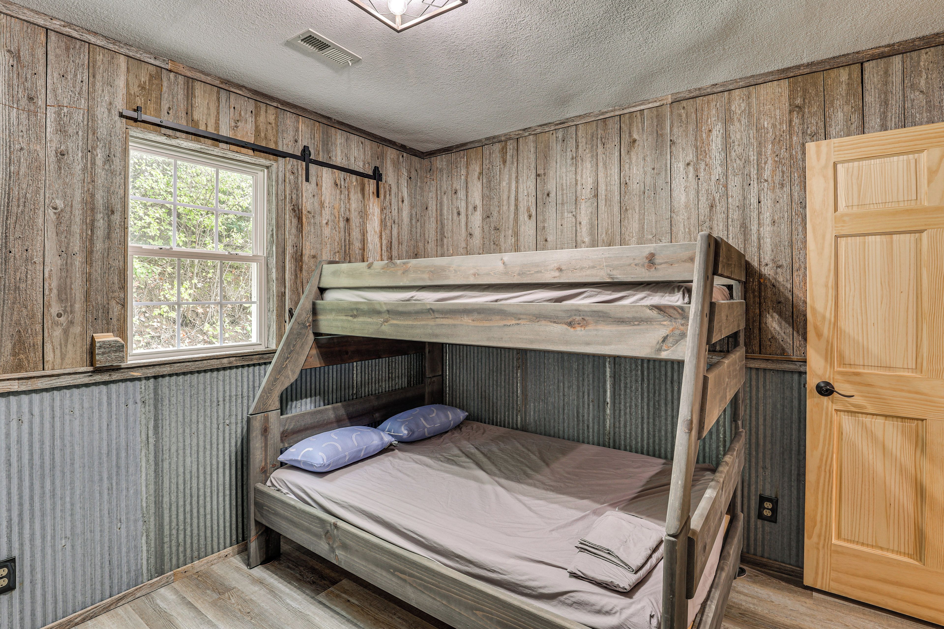 A bunk bed in a room with wooden walls, a window, and a door.