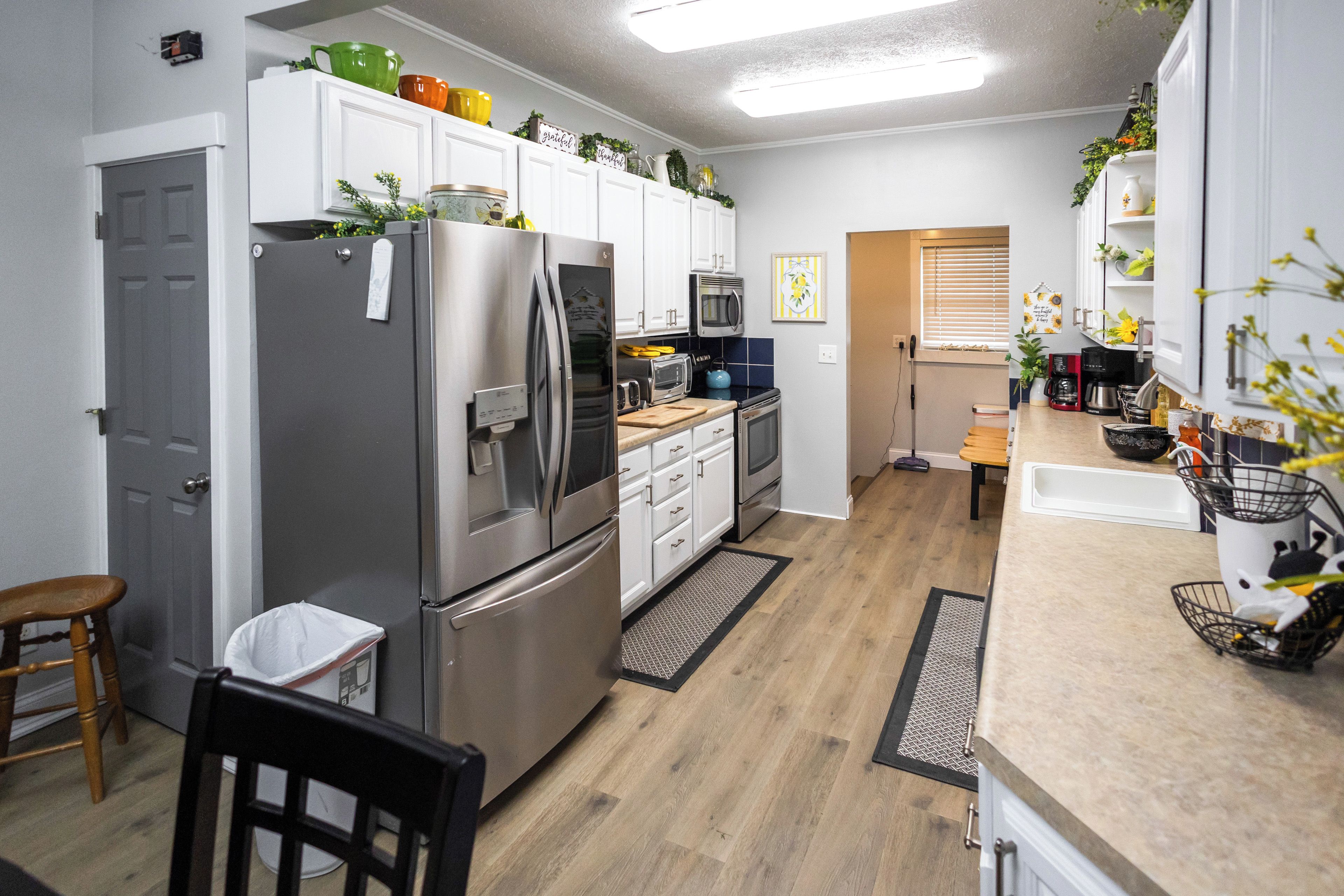 A modern kitchen with stainless steel appliances, white cabinetry, and a wooden floor.