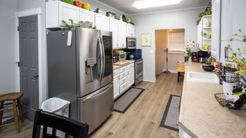A modern kitchen with stainless steel appliances, white cabinetry, and a wooden floor.
