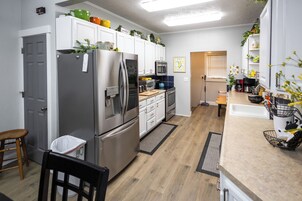 Una cocina moderna con electrodomésticos de acero inoxidable, armarios blancos y piso de madera.