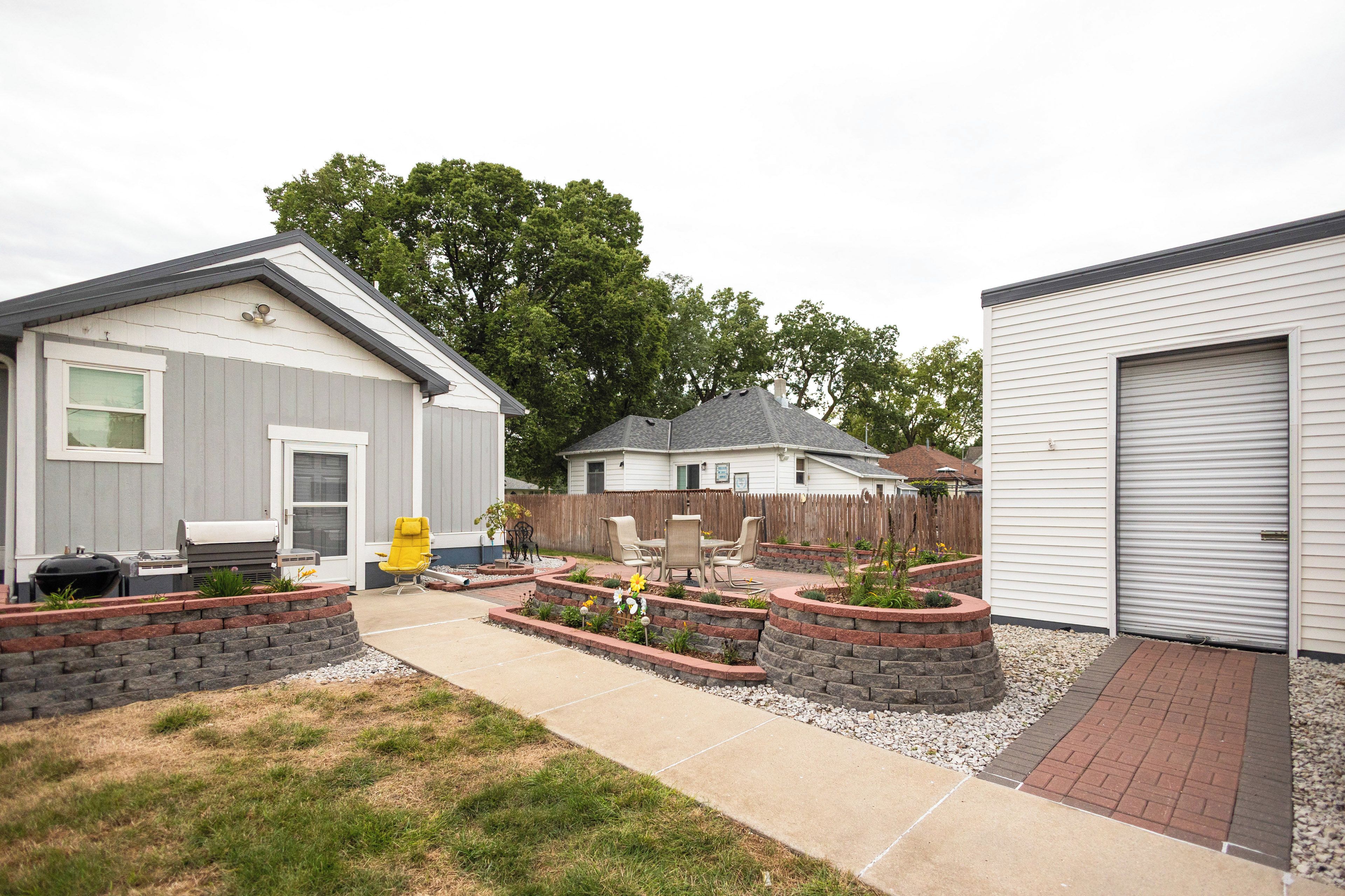 A residential backyard with a patio, outdoor seating, and a barbecue grill.