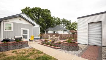 A residential backyard with a patio, outdoor seating, and a barbecue grill.