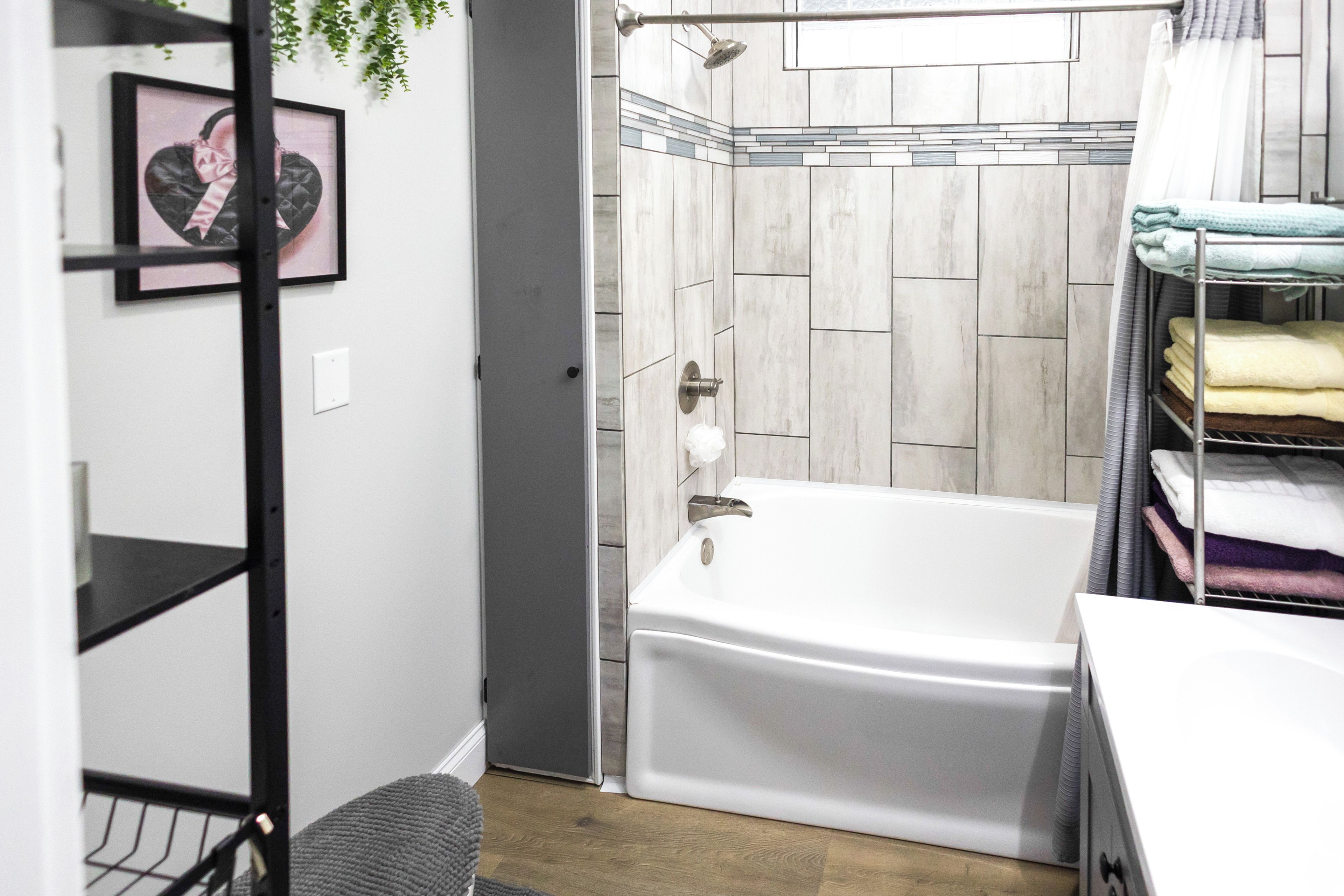 A bathroom with a bathtub, a shower, and a towel rack with folded towels.
