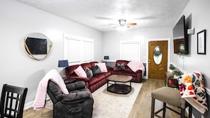 A living room with a sectional sofa, a loveseat, a coffee table, and a dining area with a chair and table. - The Play House: Family Retreat 2 Mi to Pawnee Park (Columbus)