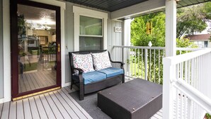 A covered porch with a wicker sofa, a small table, and a view of the backyard. - The Play House: Family Retreat 2 Mi to Pawnee Park (Columbus)