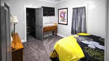 Quarto com cama, cômoda, escrivaninha, televisão e armário.