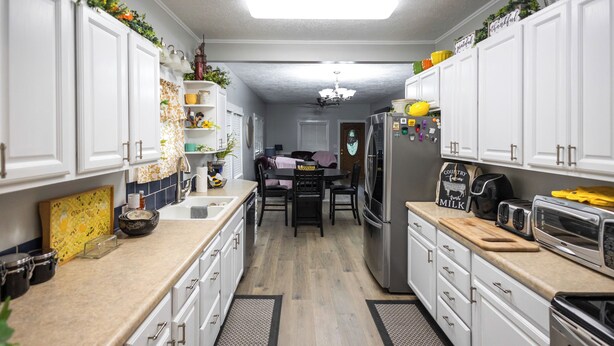 A kitchen with white cabinets, a refrigerator, a stove, and a dining area with a table and chairs. - The Play House: Family Retreat 2 Mi to Pawnee Park (Columbus)