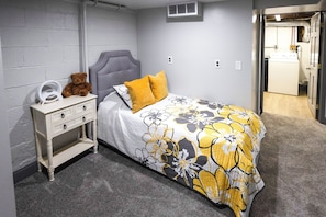 A bedroom with a bed, nightstand, and a teddy bear.