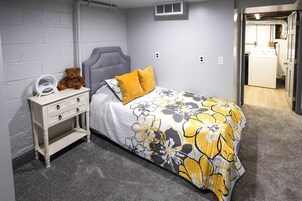 A bedroom with a bed, nightstand, and a teddy bear.