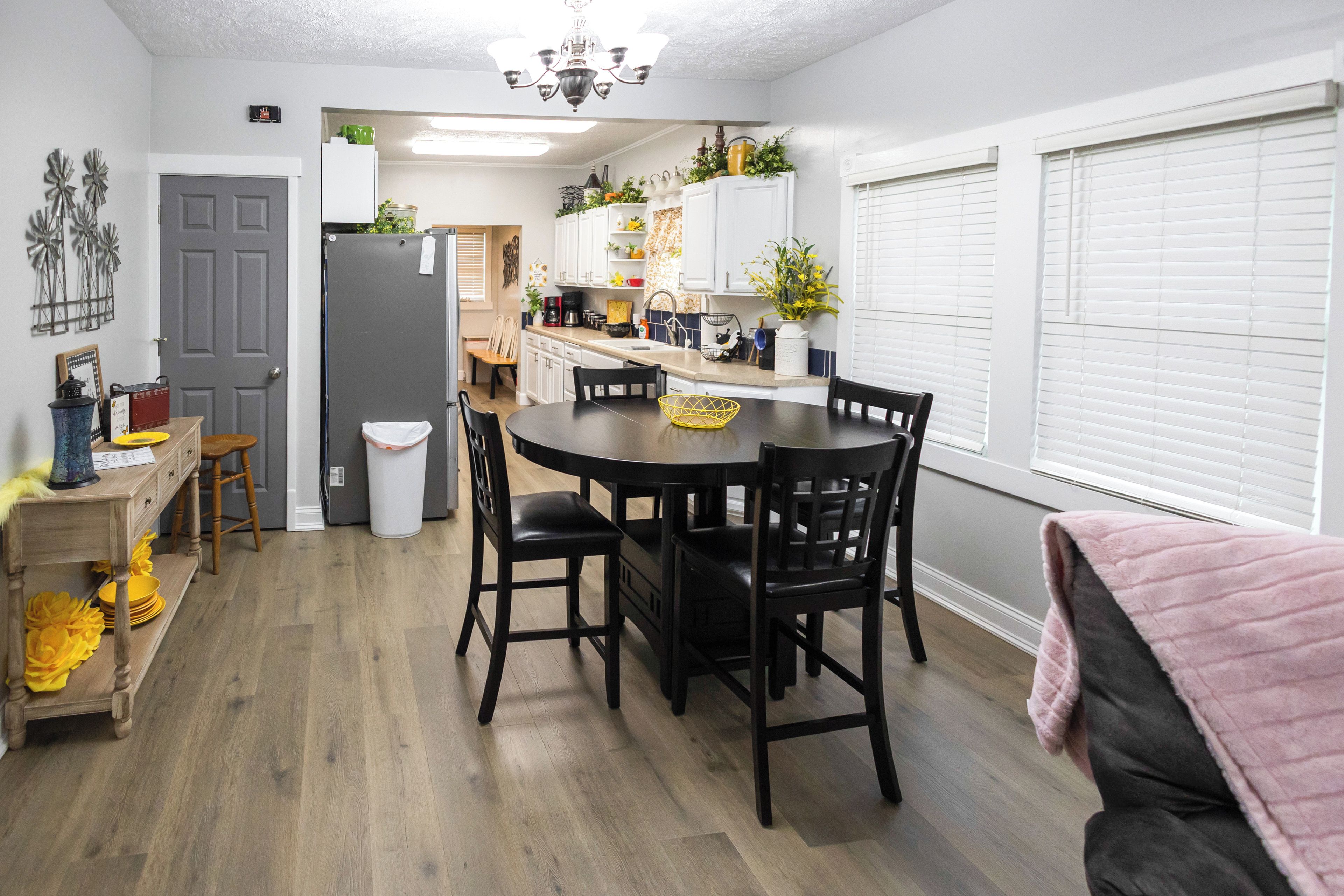 A compact kitchen with a dining table, chairs, and a refrigerator.
