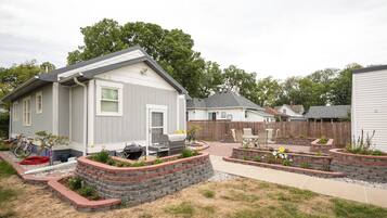 A residential area with houses, a barbecue grill, and a garden with raised flower beds.