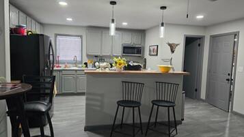 A modern kitchen with a central island, bar stools, and pendant lighting.