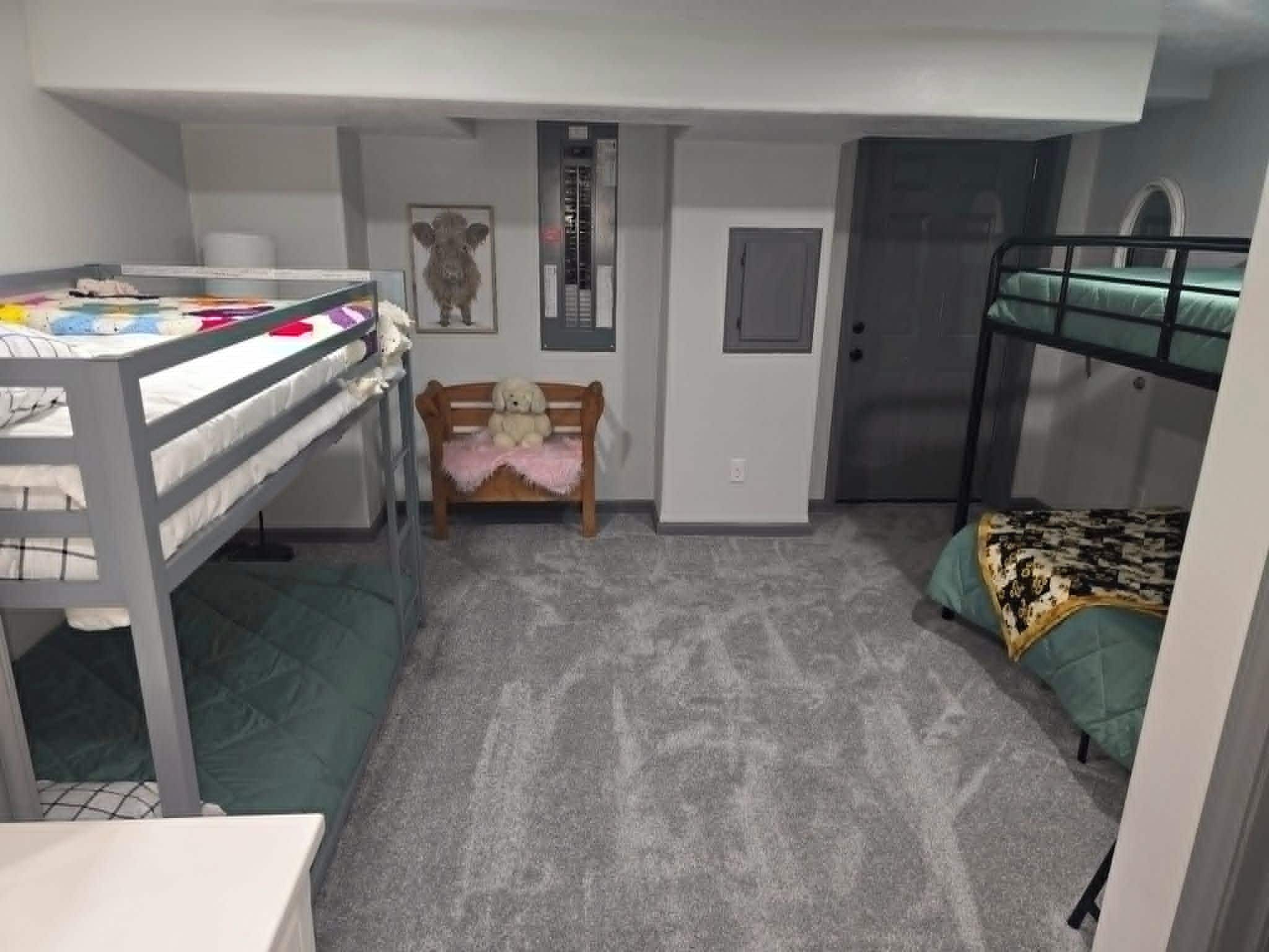 A compact room with bunk beds, a desk, a chair, and a small rug.