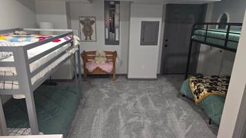 A compact room with bunk beds, a desk, a chair, and a small rug.