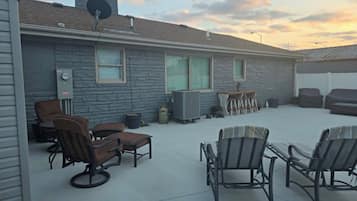 A covered patio area with outdoor furniture, a stone wall, and a satellite dish.