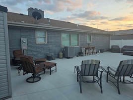 A covered patio area with outdoor furniture, a stone wall, and a satellite dish.