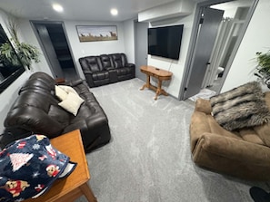 Uma sala de estar com um sofá marrom, um sofá de couro preto e uma mesa de centro de madeira.