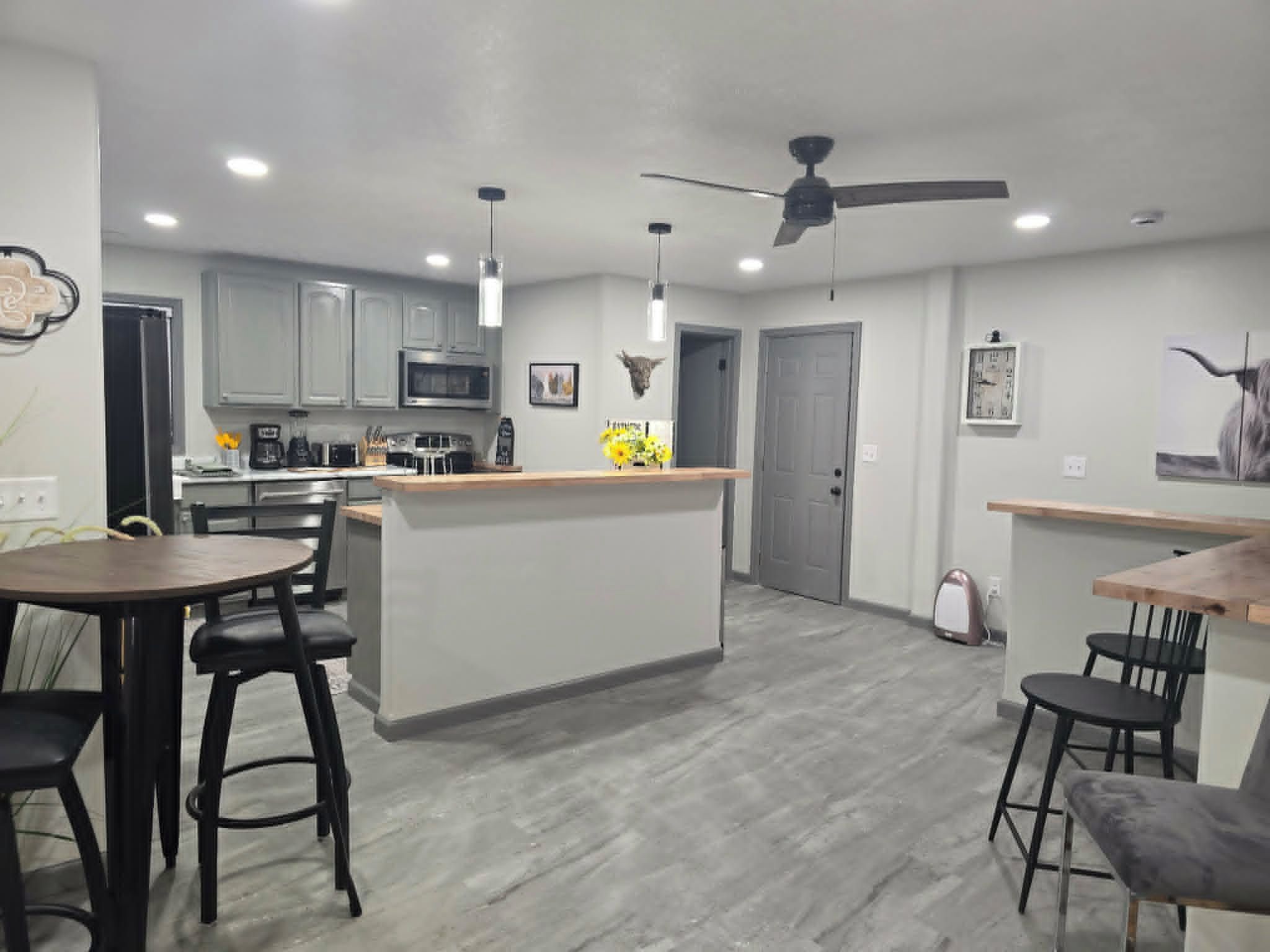 A modern kitchen with a central island, bar seating, and a ceiling fan.