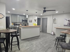 Una cocina moderna con una isla central, asientos de bar y un ventilador de techo.