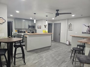 Cozinha moderna com ilha central, banquetas de bar e ventilador de teto.