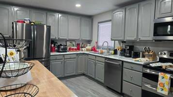 A modern kitchen with grey cabinets, stainless steel appliances, and a wooden countertop.