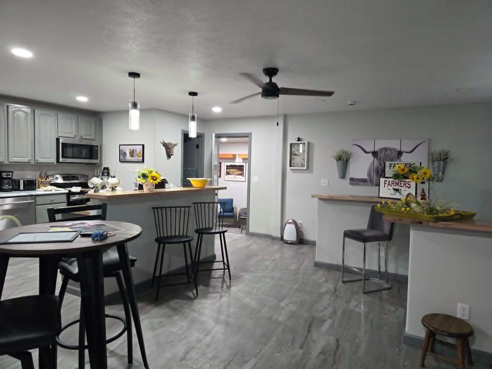 A modern kitchen with a microwave, stove, and dining area with chairs and a table.