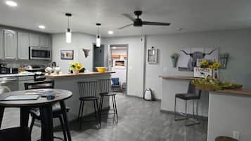 A modern kitchen with a microwave, stove, and dining area with chairs and a table.