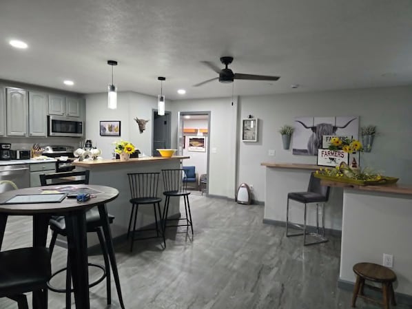 Cozinha moderna com micro-ondas, fogão e área de refeições com cadeiras e mesa.