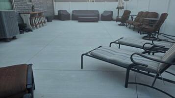 A patio area with lounge chairs and a barbecue grill.