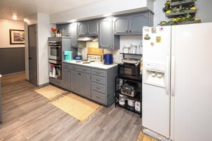 Una cocina con gabinetes grises, un refrigerador blanco y una cafetera.