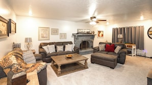 A living room with a fireplace, multiple sofas, a coffee table, and a ceiling fan. - 'the Cech Inn' in Columbus: Walk to Pawnee Park! (Columbus)