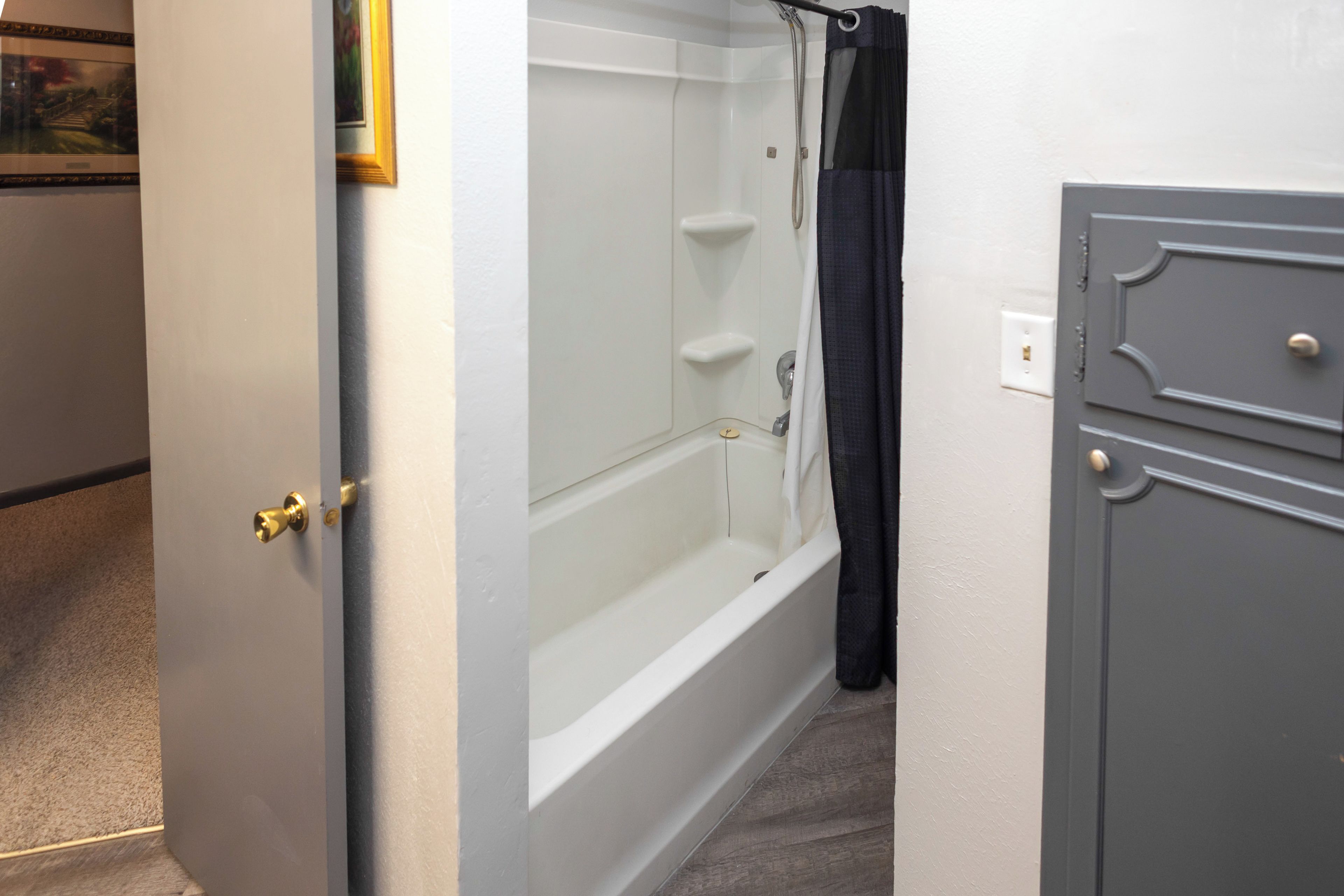 A bathroom with a bathtub, a shower, and a door with a handle.